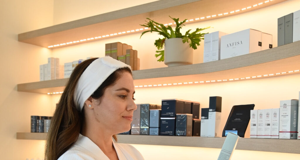 Client browsing medical-grade skincare on the illuminated retail shelves at L&P Aesthetics